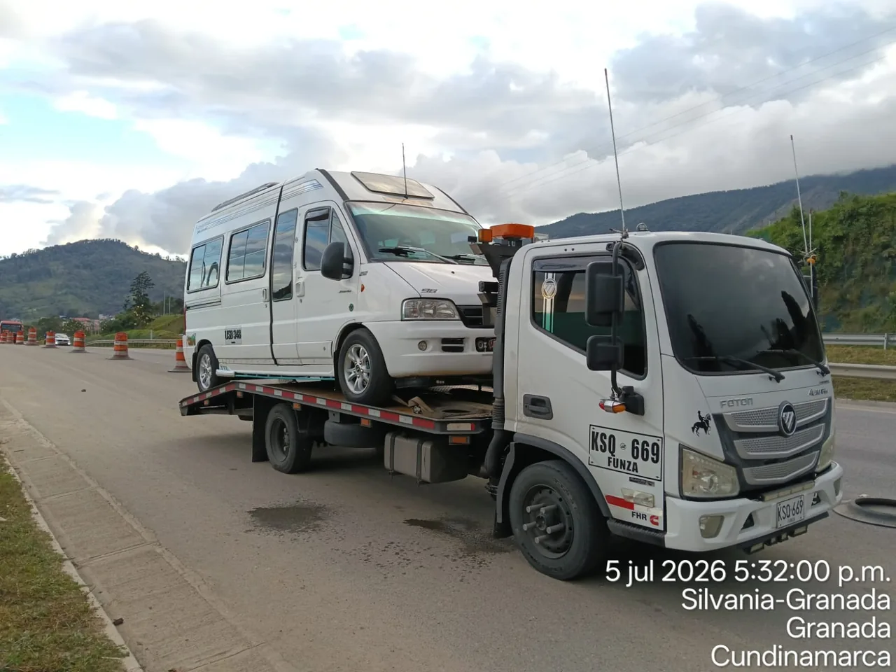 Minibús blanco transportado sobre plataforma de grúa